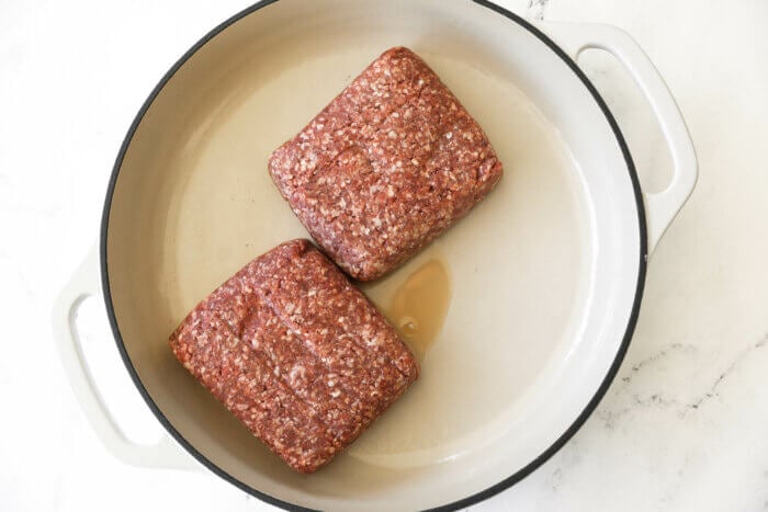 Two ground beef cubes in a white skillet