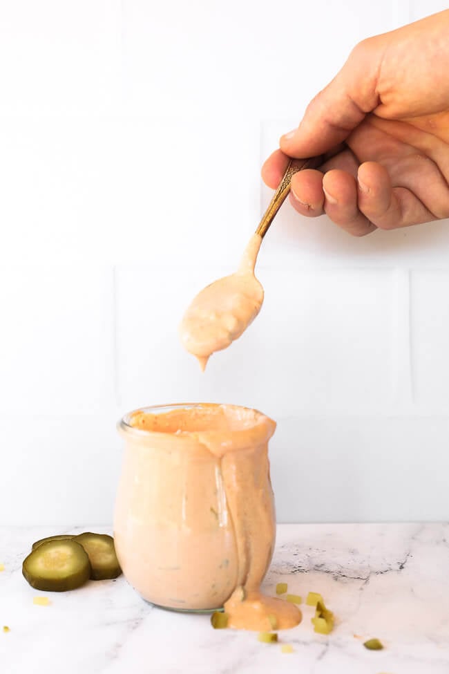 sauce in jar with hand holding spoon above