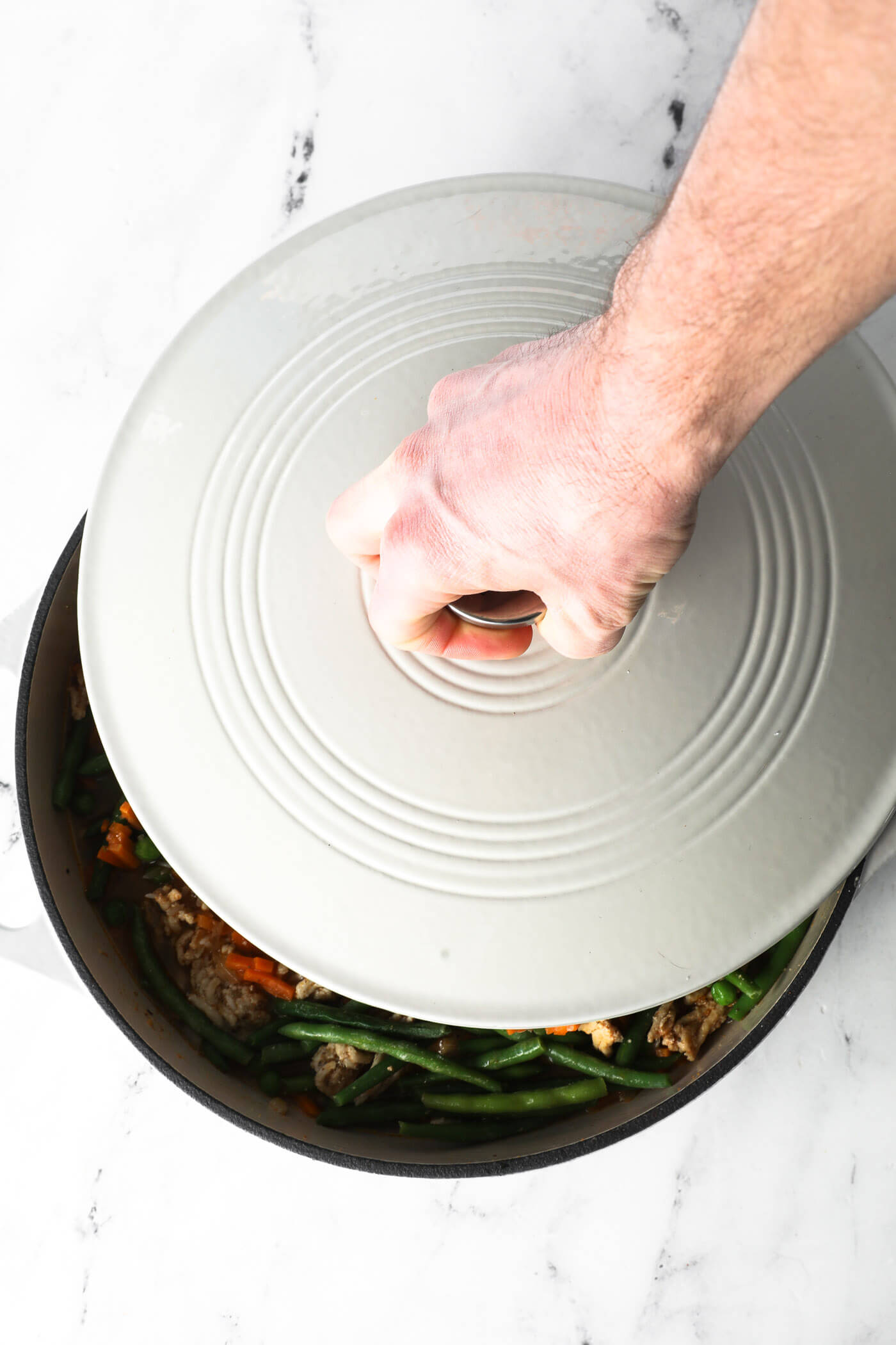 Placing the lid on the skillet.