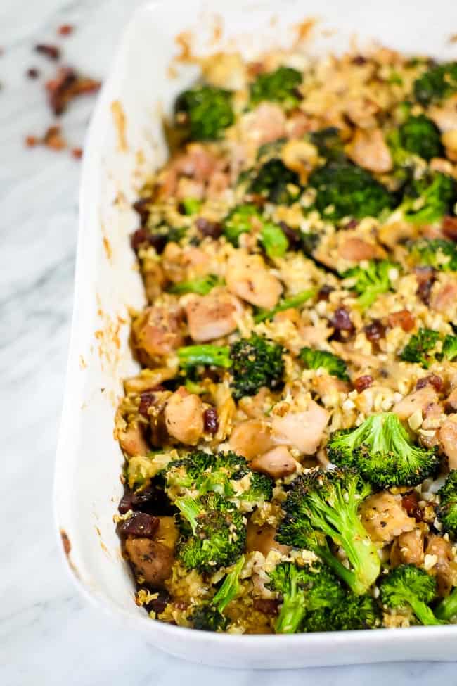 Healthy chicken and broccoli casserole with bacon and cauliflower rice in a creamy sauce in a casserole dish. 