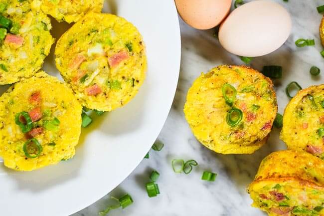 Healthy egg muffins on a plate and on the table with eggs and chopped green onion.