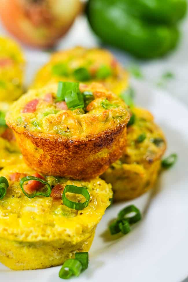 Muffins aux œufs sains sur une assiette d'oignons verts hachés.