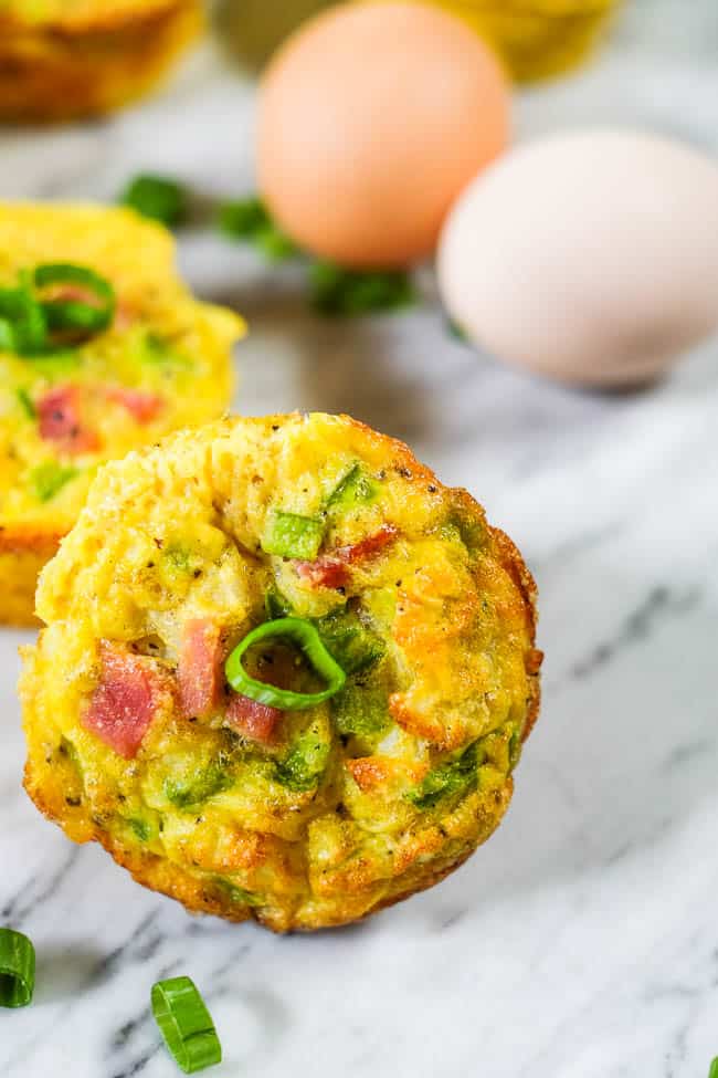 muffins de ovo saudáveis sobre a mesa com ovos e cebola verde picada.