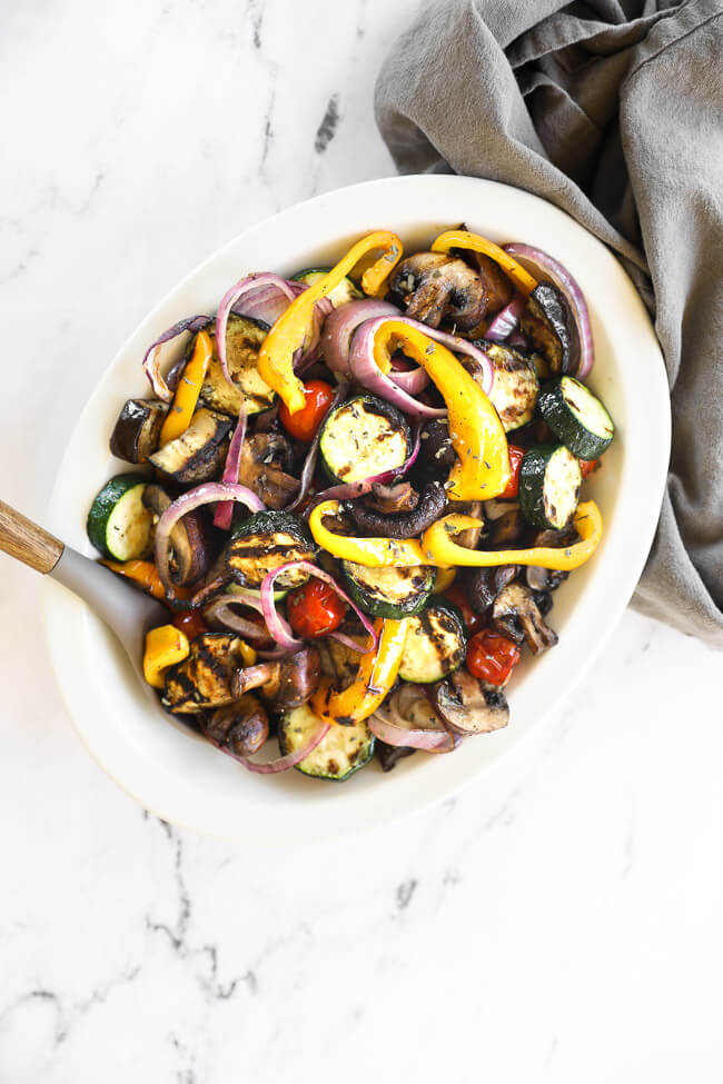 Overhead image of an oval bowl full of grilled veggies tossed in a marinade. 