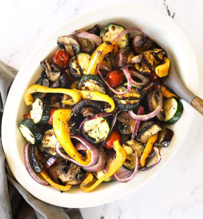 Overhead shot of oval bowl with grilled vegetable marinade tossed in grilled veggies