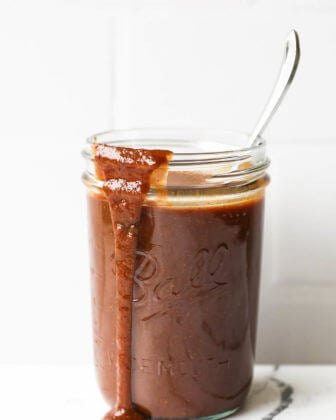Healthy homemade whole30 BBQ sauce in a jar with spoon and sauce running down front of jar