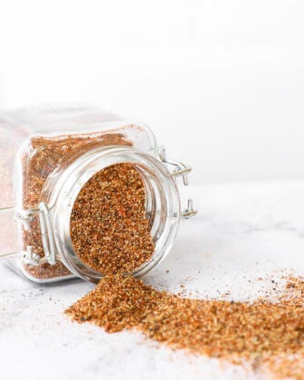Homemade taco seasoning in a jar tipped over on side with seasoning spilling out