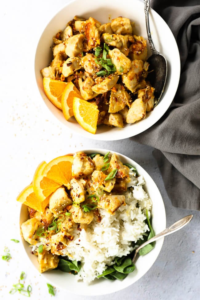 Two bowls of orange chicken, one with rice and a spoon