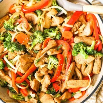 Marinated chicken stir fry with broccoli, onion and bell pepper in a skillet with spoon