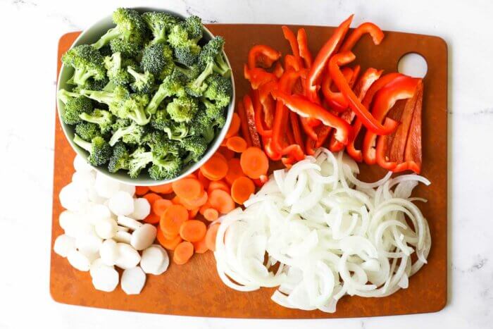 Chopped broccoli, water chestnuts, carrots, onion and red bell pepper on a board