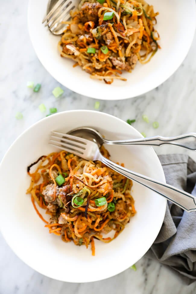 Healthy pork casserole in bowls with forks on side and green onion topping overhead shot