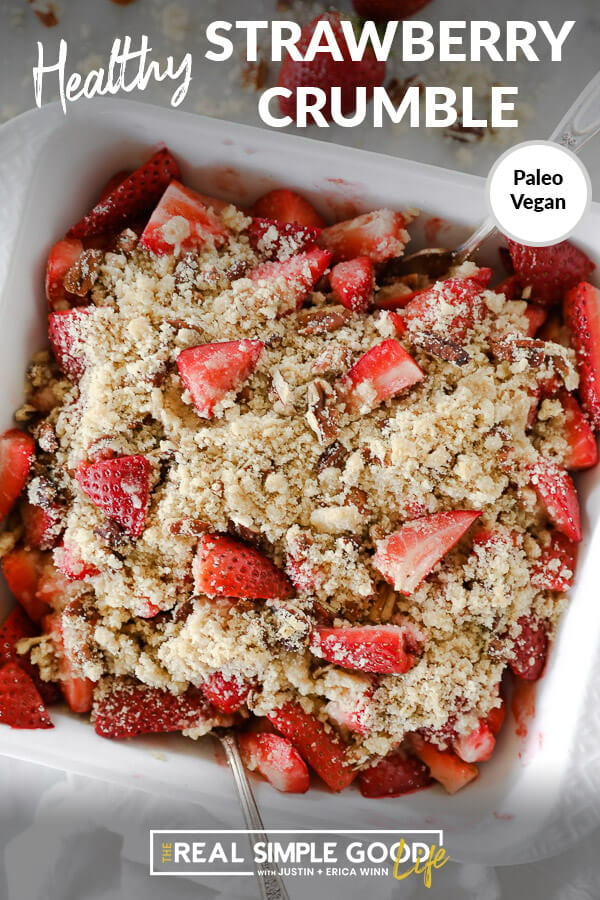 Vertical overhead image with text overlay at top that says "Healthy Strawberry Crumble - Paleo + Vegan". Image of crumble in baking dish with two spoons dug in. 