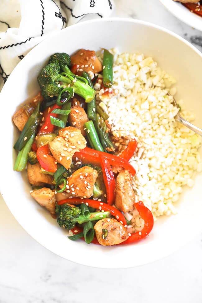 Overhead image of teriyaki chicken stir fry served in a bowl with cauliflower rice. 