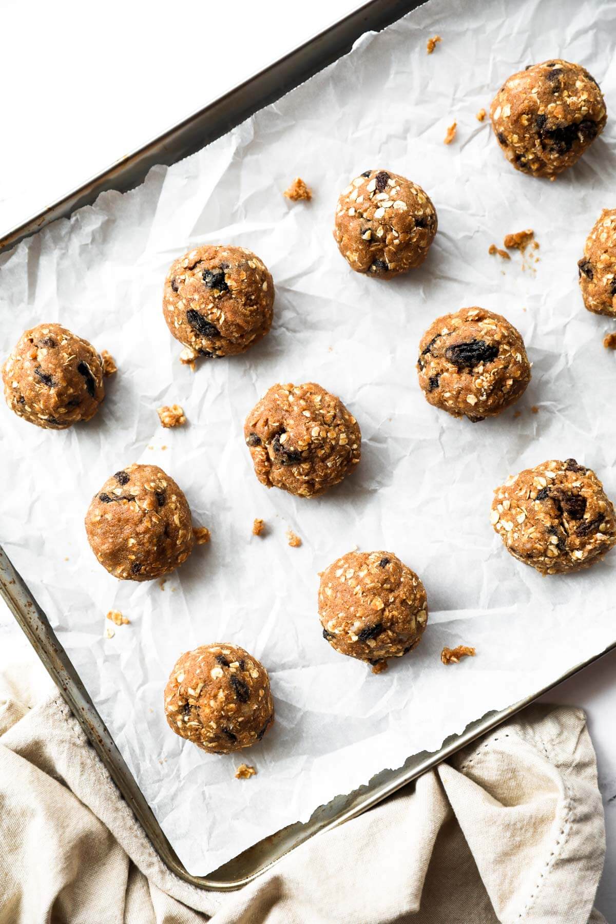Vegan, healthy oatmeal cookies are rolled into balls and placed on a cookie sheet before baking.