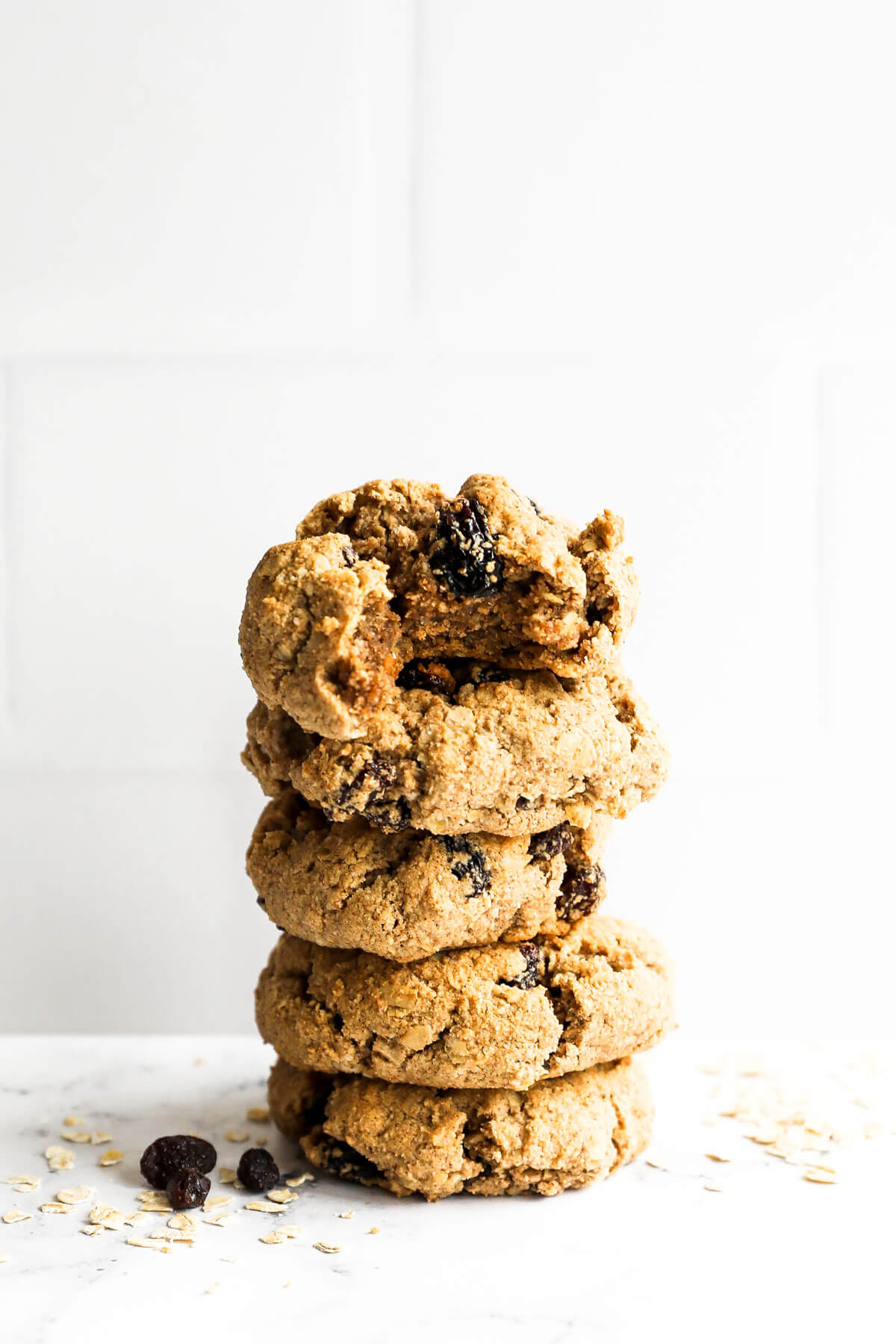 Stack of healthy oatmeal raisin cookies. The top cookie has a bite taken out of it.
