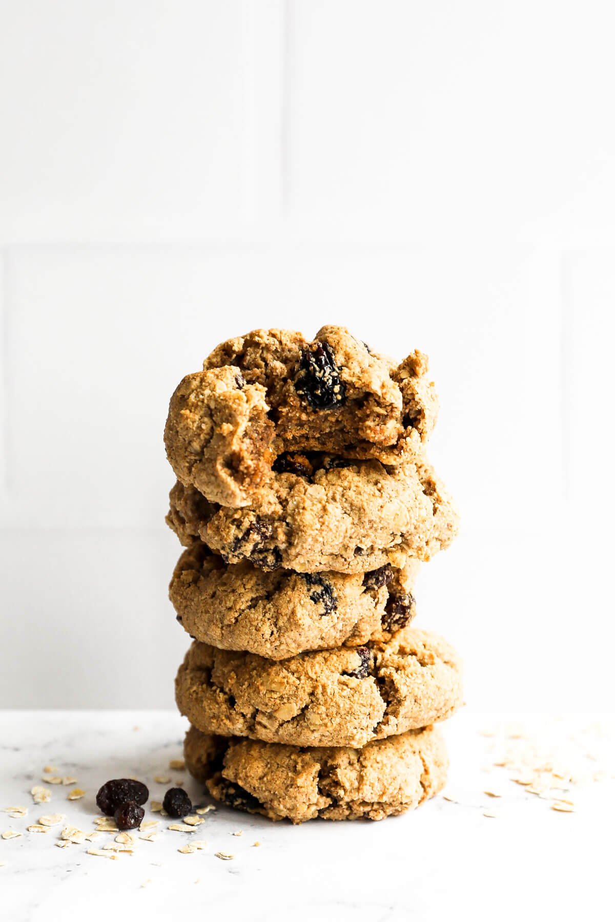 Stack of healthy oatmeal raisin cookies. The top cookie has a bite taken out of it.