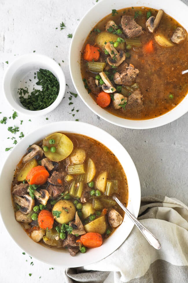Two bowls filled with hearty beef soup with vegetables