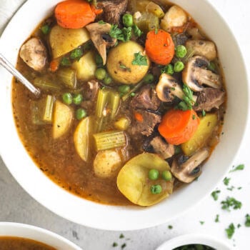 Overhead close up of hearty instant pot beef and vegetable soup with potatoes, carrots, celery mushrooms and peas