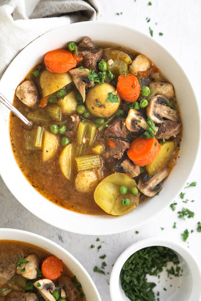 Overhead close up of hearty instant pot beef and vegetable soup with potatoes, carrots, celery mushrooms and peas