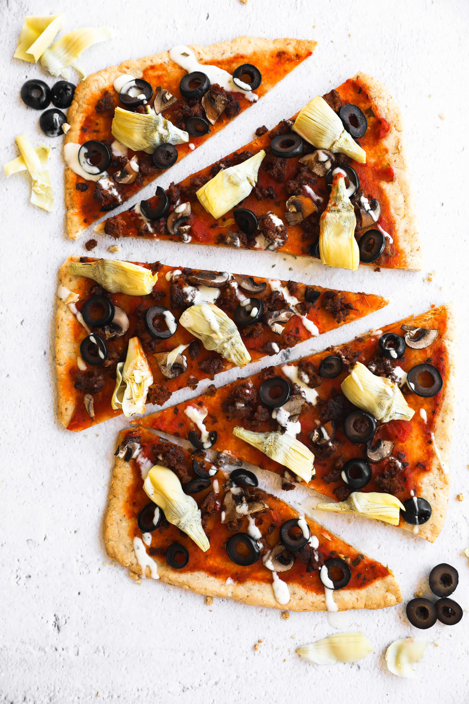 Vertical image of pieces of flatbread pizza scattered. 