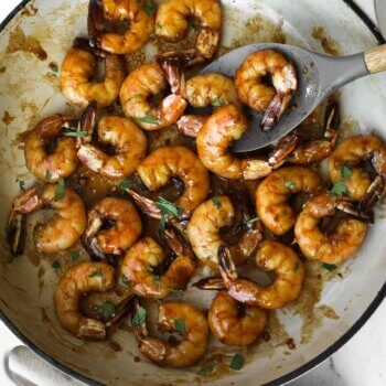 Overhead image of cooked honey garlic pan fried shrimp in a pan with chopped cilantro
