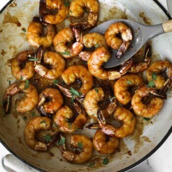 Overhead image of cooked honey garlic pan fried shrimp in a pan with chopped cilantro