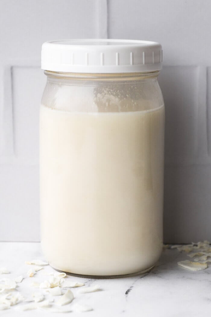 Coconut milk in a mason jar for storage with a plastic lid.