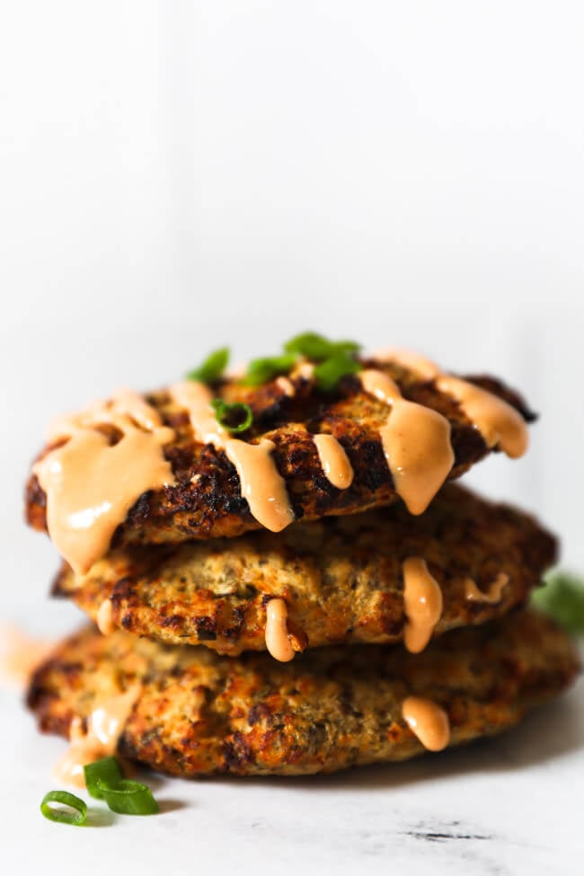 Stack of 3 air fryer salmon patties with sauce on top dripping down