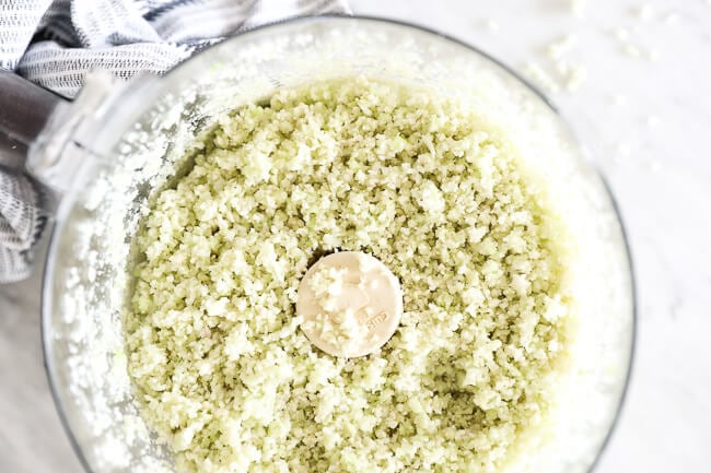 Horizontal overhead image of cauliflower rice in a food processor. 