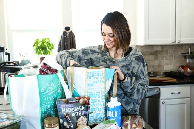 Person unloading grocery bags in kitchen