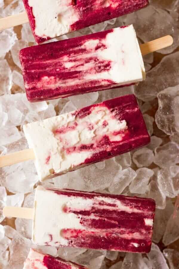 Red and white cherry creamsicles in a vertical line sitting on ice