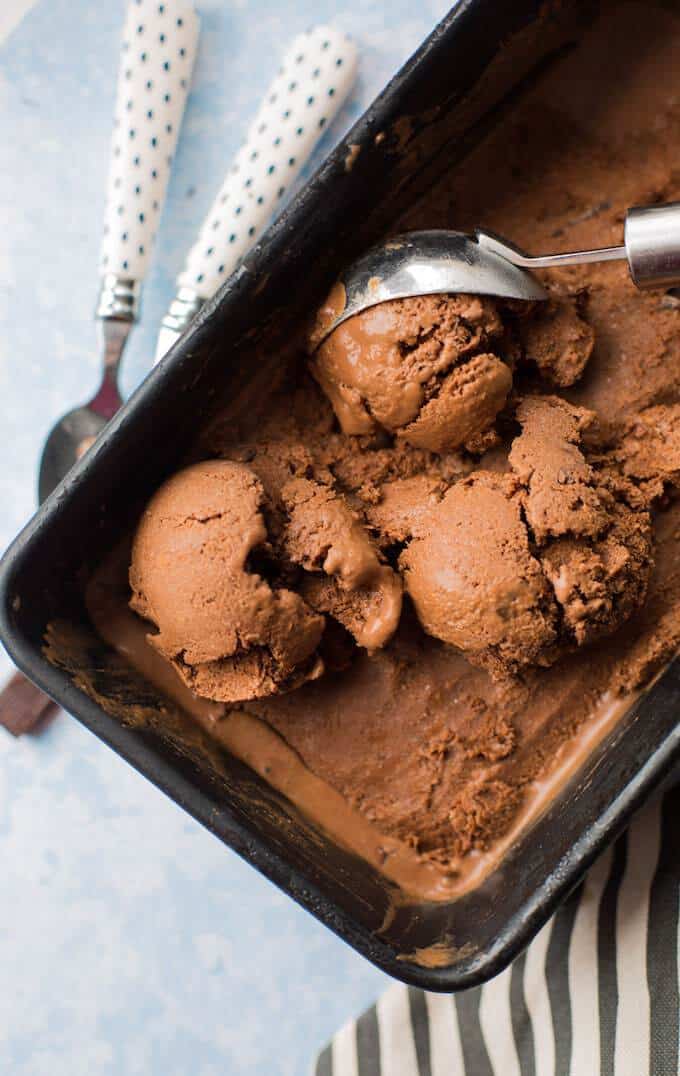 Chocolate ice cream in a loaf pan with a scoop being made
