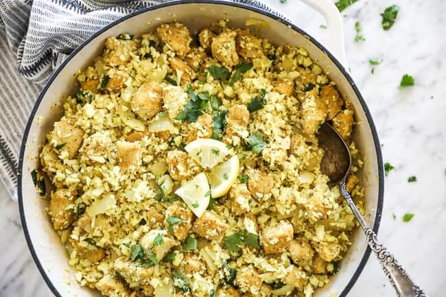 Indian chicken in pan with spoon and cilantro and lemon topping horizontal image