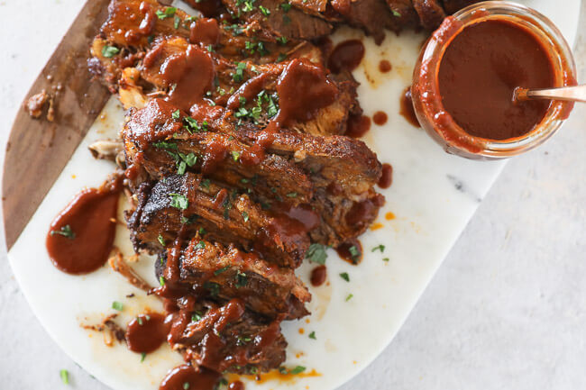 Instant pot beef brisket sliced on a board with BBQ sauce on top horizontal overhead image
