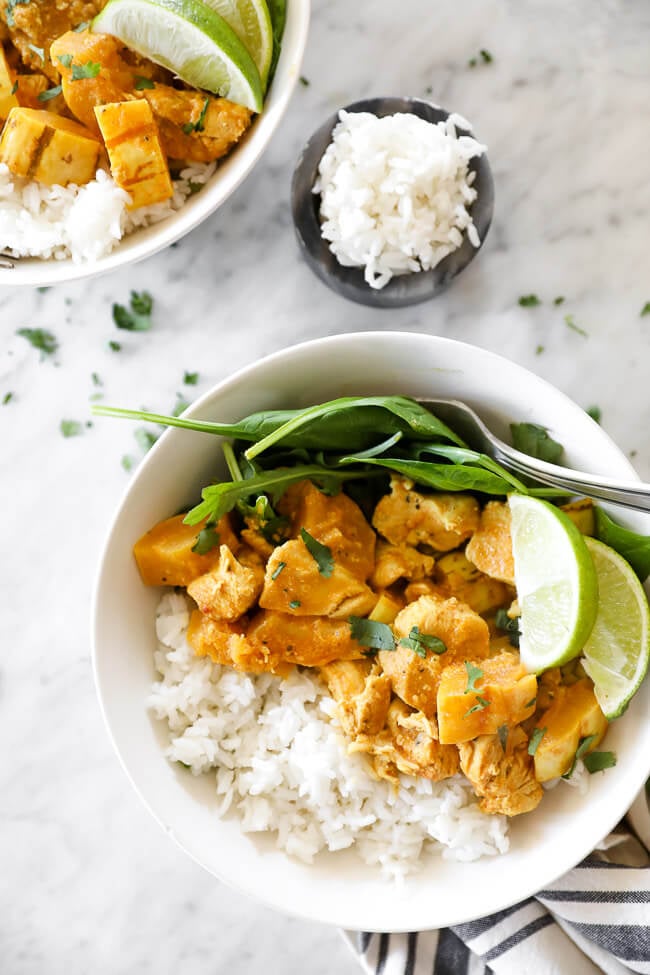 Instant pot chicken curry in bowl with rice, spinach and lime horizontal close up image