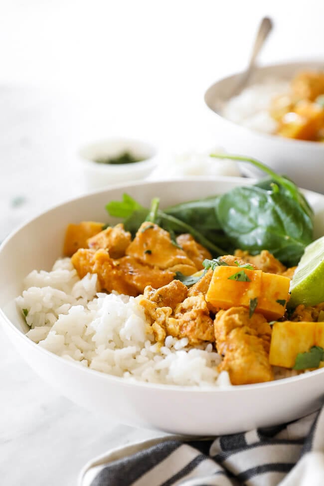 Instant pot chicken curry in bowl with rice, spinach and rice close up vertical image at angle