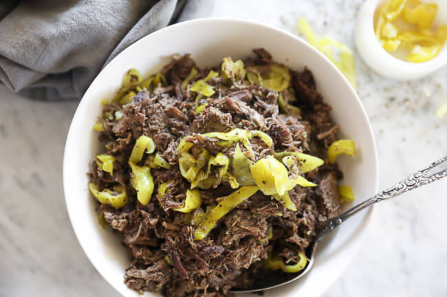Instant pot italian beef shredded in a bowl with peppers and spoon horizontal overhead image