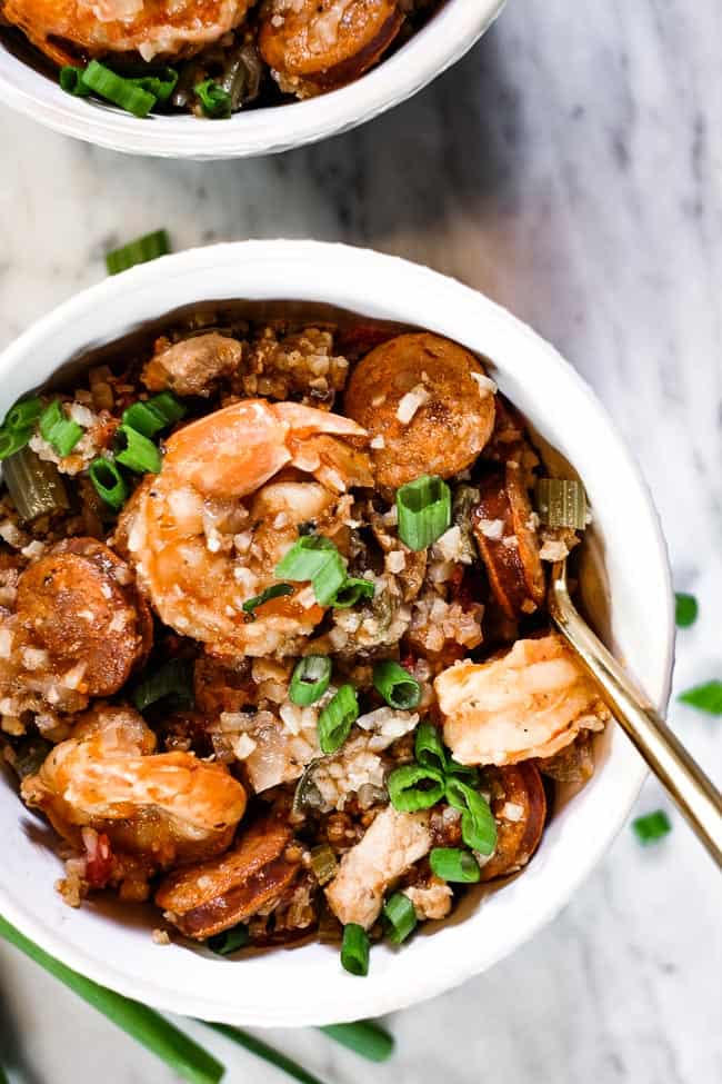 Instant pot jambalaya served in a couple bowls with chopped green onion garnish and forks. 