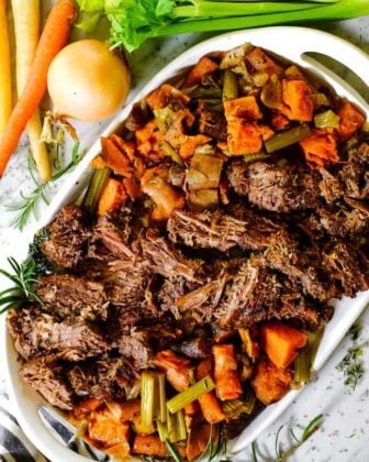Shredded instant pot pot roast on a platter with carrots and celery