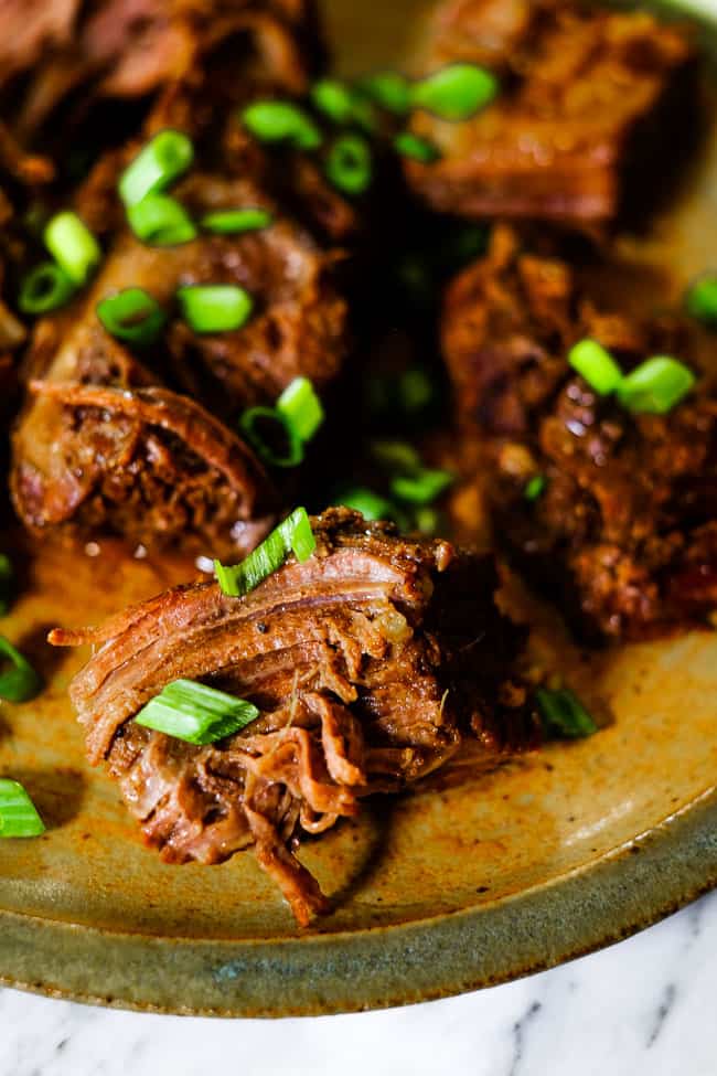 Instant pot short ribs on a plate garnished chopped green onion. 