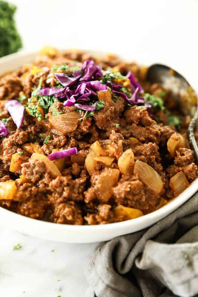Sloppy joes in a bowl with spoon and chopped purple cabbage topping