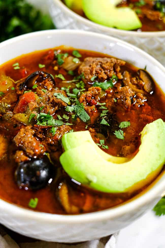 Angled shot of Instant Pot taco soup in bowl with sliced avocado and chopped cilantro. 