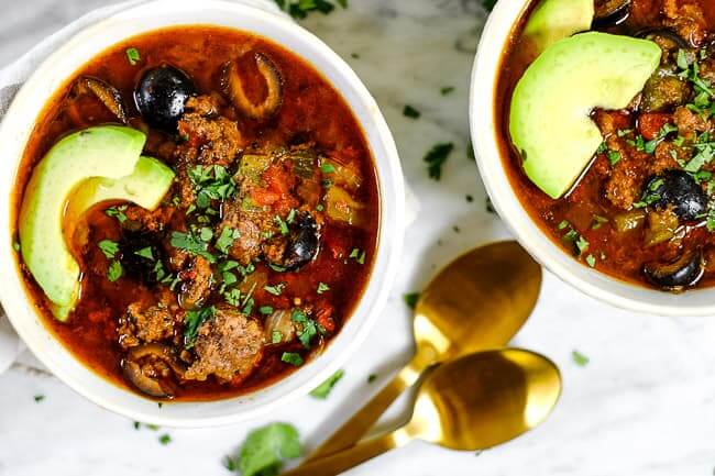 Instant pot taco soup in two bowls with avocado slices, fresh chopped cilantro and two spoons. 