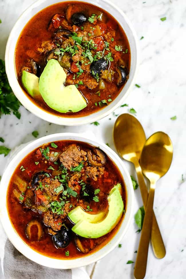 Instant Pot taco soup in two bowls with sliced avocado, chopped cilantro and two spoons. 