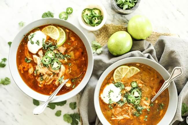 Instant pot white chicken chili horizontal image with 2 bowls  with toppings and spoons sticking out. 