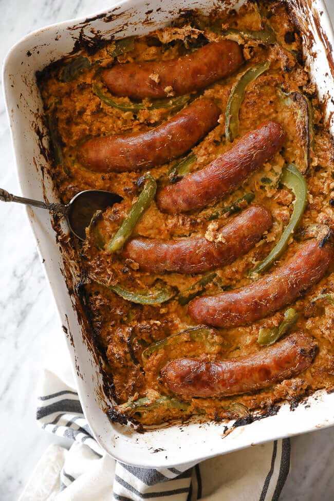 Sausages and bell peppers in a casserole dish over creamy cauliflower overhead vertical image