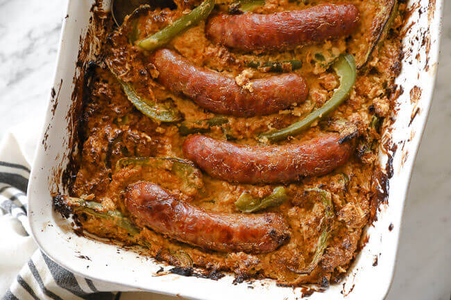 Sausages and bell peppers in a casserole dish over creamy cauliflower