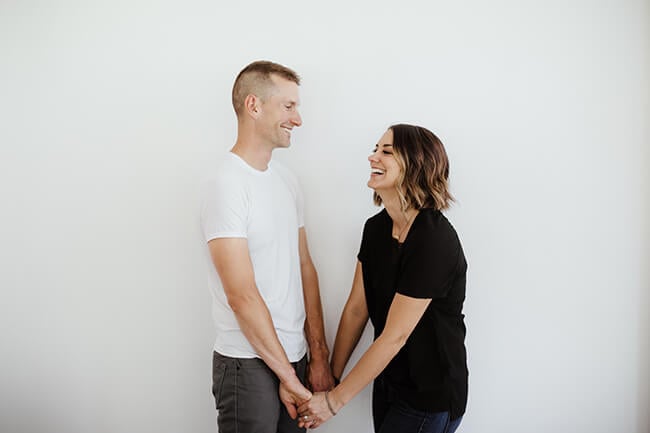 Horizontal image of Justin and Erica Winn facing each other, holding hands and laughing. 