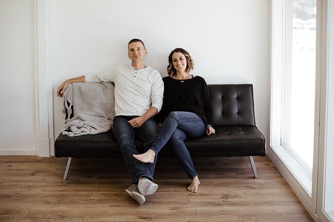 Horizontal image of Justin and Erica Winn sitting on black couch.