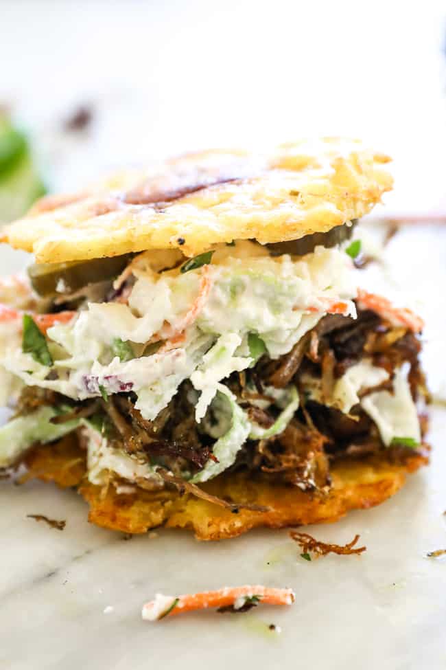 Straight on shot of jibarito with plantain buns, pulled pork, slaw and pickles. 